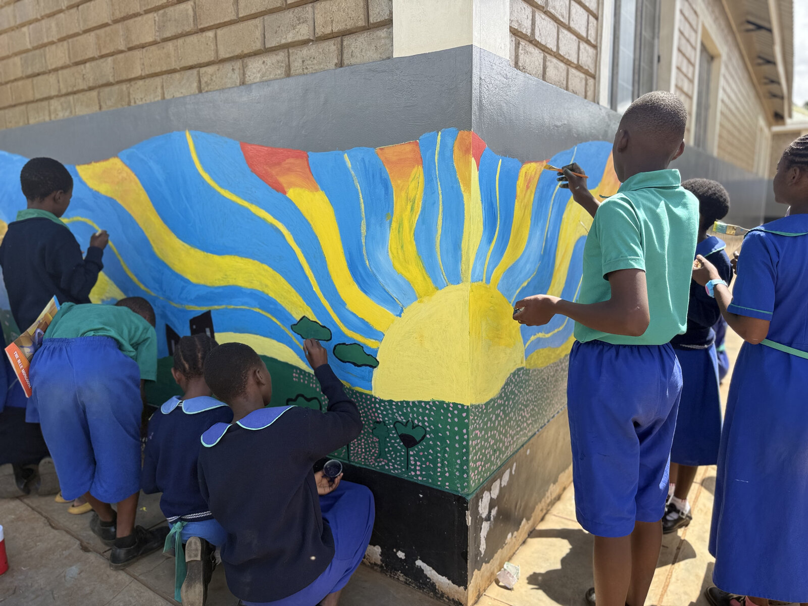 Students painting a group mural, Kenya